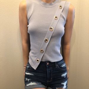 Gray sleeveless blouse with gold rings.